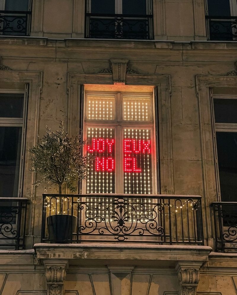 Porte-fenêtre qui affiche Joyeux Noël en lettres rouges au-dessus d'un balcon